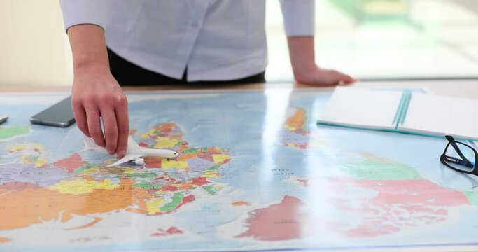 Toy plane in hand against the background of world map.