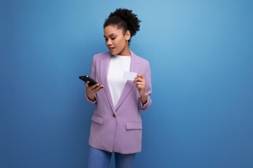 young successful positive office woman dressed in a jacket pays for purchases using a smartphone and a credit card