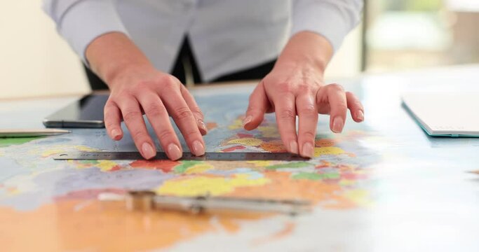 Woman with ruler takes measurements on world map