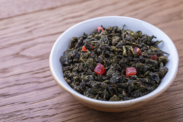 Dried natural large tea leaves close up. Chinese tea Tie Guan Yin with strawberry pieces. 