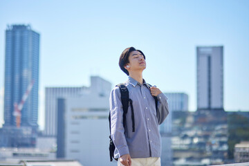 ワイヤレスイヤホンで音楽を聴く通学中の日本人大学生の男性