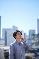 ワイヤレスイヤホンで音楽を聴く通学中の日本人大学生の男性