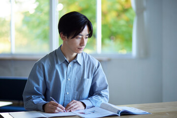 家のリビングで勉強をする日本人大学生の男性