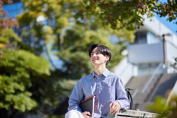 大学キャンパスのベンチに座る日本人大学生の男性