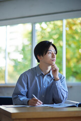 家のリビングで勉強をする日本人大学生の男性