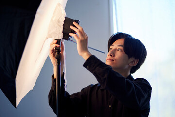 写真スタジオにてストロボの調整を行う日本人フォトグラファーの男性