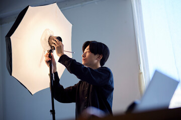 写真スタジオにてストロボの調整を行う日本人フォトグラファーの男性 - obrazy, fototapety, plakaty