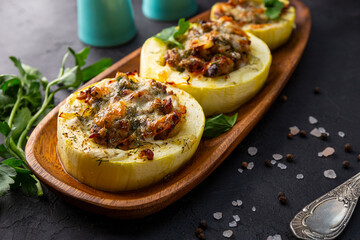 Round zucchini baked with minced meat and cheese on the black background