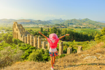 Tourist girl, enchanted by the ancient marvels of Turkey, explores the impressive Roman aqueduct of...