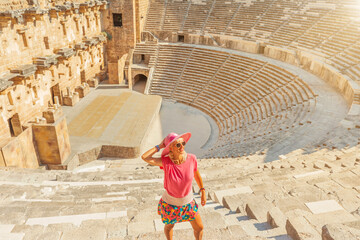tourist girl visiting Roman Theatre Aspendos in Turkey has seating arrangement for 7000 spectators, exceptional acoustics, even a whisper from stage can be heard clearly throughout Aspendos auditorium