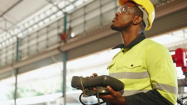engineer controls a robot using a control board inside a factory.

