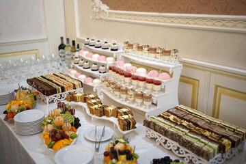 Beautiful and delicious sweet donuts are laid out on the wooden shelves of the buffet table.