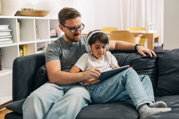 Obraz premium A man helps his son to use digital tablet.