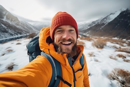 Generative AI image of a Young man wearing winter clothes taking selfie picture in winter snow mountain - Happy guy with backpack hiking outside - Recreation, sport and people concept