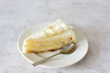 creamy coconut cake on white saucer with teaspoon isolated   