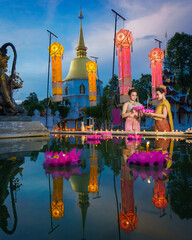 Naklejka premium Pretty Asian Thai women holding a Krathong floating on water, Asian women in traditional Thai dress bring Krathong to float on Loy Krathong Festival Day, Popular traditions culture of Thailand.