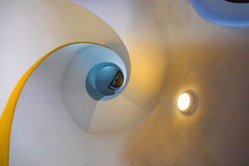 View up to very high and light spiral staircase inside high and old renovated lighthouse next to sea