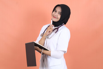 doctor wearing white suit uniform with stethoscope, waist up and smiling with writing recipe on...