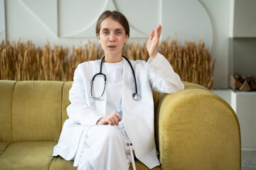 Portrait of a female doctor talking online with a patient, making a video call, looking into the...