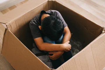 Foto op Plexiglas Little boy sitting alone hugging knee in the box. Mental health concept.  © Queenmoonlite Studio