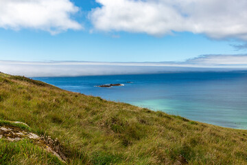 Fototapeta na wymiar Sea mist over the ocean and a blue sky overhead, at Sennen on the Cornish coast