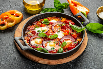 Shakshuka fried eggs with vegetables in frying pan on a dark background. top view. copy space for text