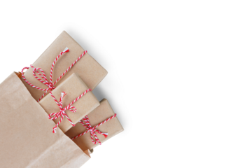 Christmas gift boxes wrapped in craft paper with striped red and white baker's twine in brown recycled paper bag isolated on white, transparent background, PNG. Flat lay, top view