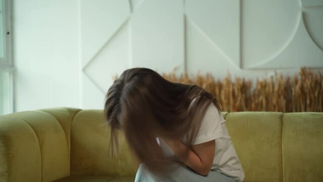 Woman sneezes while sitting on the sofa in the living room and suffering from the flu and runny nose. 