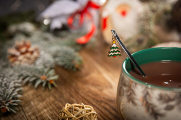 Hot chocolate in a white Christmas mug with a spoon with a Christmas tree pendant on a wooden table...
