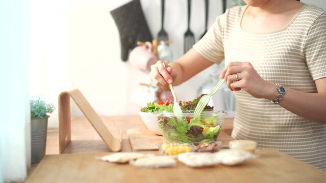 Woman making a salad in kitchen.