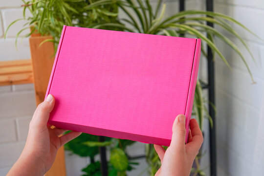 Mockup pink cardboard box in a delivery hand, delivery service concept photo