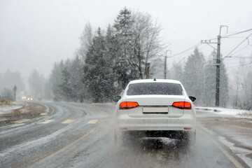 The first winter snow on a country road, a car under the snow.