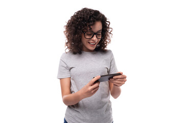 serious curly brunette promoter woman with glasses dressed in a gray t-shirt watches video on a...