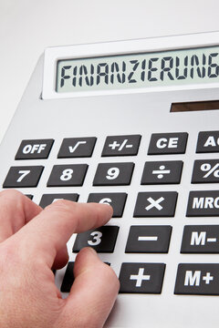 Hand bedient übergroßen Taschenrechner zur Kalkulation einer Finanzierung, das Display des Taschenrechners zeigt das Wort "Finanzierung".