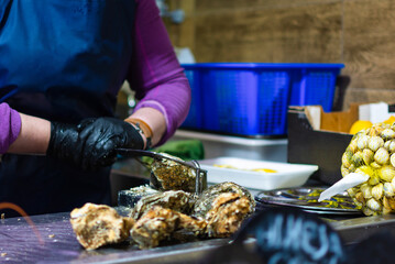 An expert hand deftly handles a tool to open an oyster in a traditional market