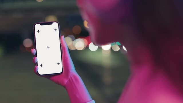 In the city night, a closeup captures a woman showcasing a smartphone with trackable points, ideal for app mockup templates