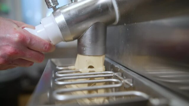 Closeup indoor shot of pasteurizer machine pouring ice cream into steel freezer. Ice cream manufacture concept. High quality 4k footage