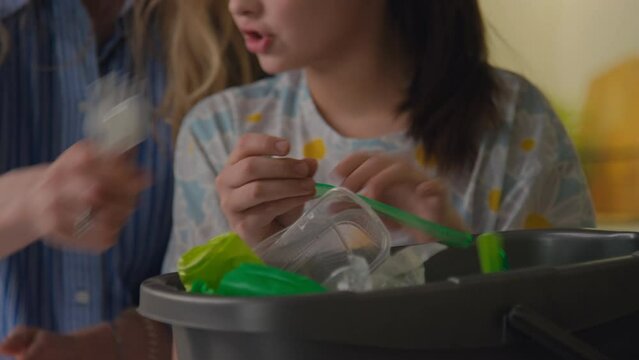 Selective focus of unrecognizable teenage girl and female adult sorting plastic waste into different trash bins