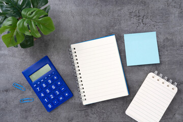 Calculator and notebook on stone texture background. Flat lay of a workplace. Accounting workplace...