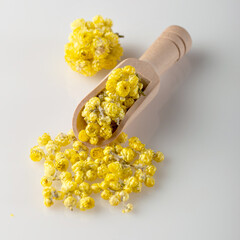 Medicinal immortelle flowers lie on the table in a scoop. Dried grass..Immortelle flowers are used for making teas, decoctions and infusions. Healing herbs