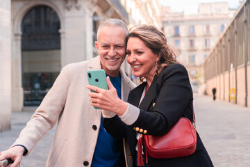 Mature couple tourists looking at mobile phone. Adult marriage smiling and laughing with a smartphone in a weekends trip. Man and woman enjoying their holidays