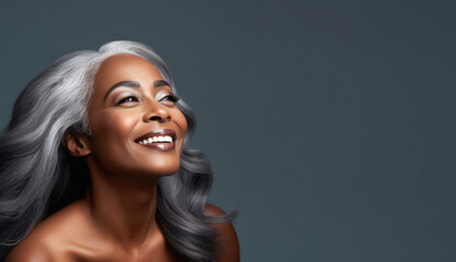Fototapeta premium Portrait of an elegant mature woman with smooth healthy skin, long gray hair, and a joyful smile. Cosmetics and beauty advertising.