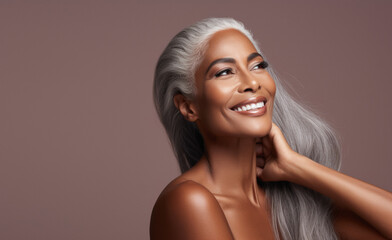 Portrait of an elegant mature woman with smooth healthy skin, long gray hair, and a joyful smile. Cosmetics and beauty advertising.