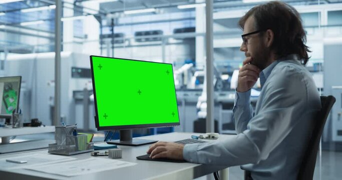 Software Developer Working on a Desktop Computer with Green Screen Mock Up Template Display in an Industrial Plant. Technological Research and Development Office Monitoring the Production Process