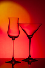 Empty glass wine glass on a red background..Wine glass for a drink on a red background. Dark silhouette of a glass.