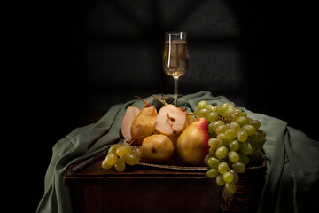 Still life with fruit and wine in retro style.Juicy fruits lying on the table. Still life of pears, grapes and wine.