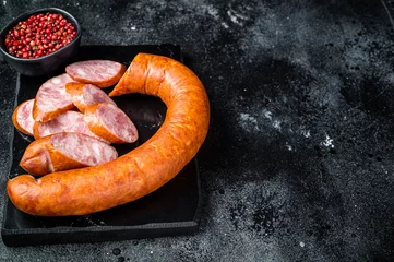 Fotobehang Smoked sausage on a marble board. Black background. Top view. Copy space © Vladimir