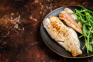 Roasted Snapper, sea red perch fillet on a plate with salad. Dark background. Top view. Copy space