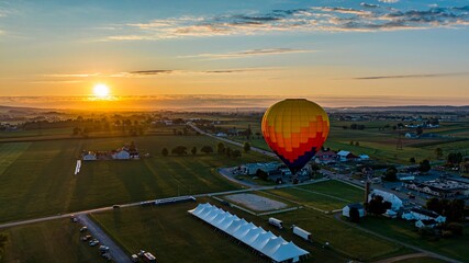 An Aerial View of a Multi-Colored Hot Air Balloon, Floating Over Pennsylvania Farmlands at Sunrise,...