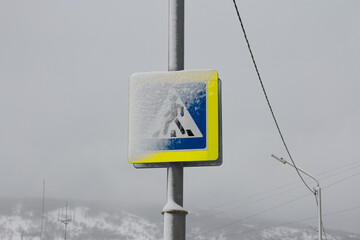 Picture of winter snowy Magadan city, Russia. Road sign covered with snow. Pedestrian walkway or...